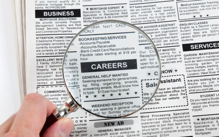 Magnifying glass held over black and white news paper